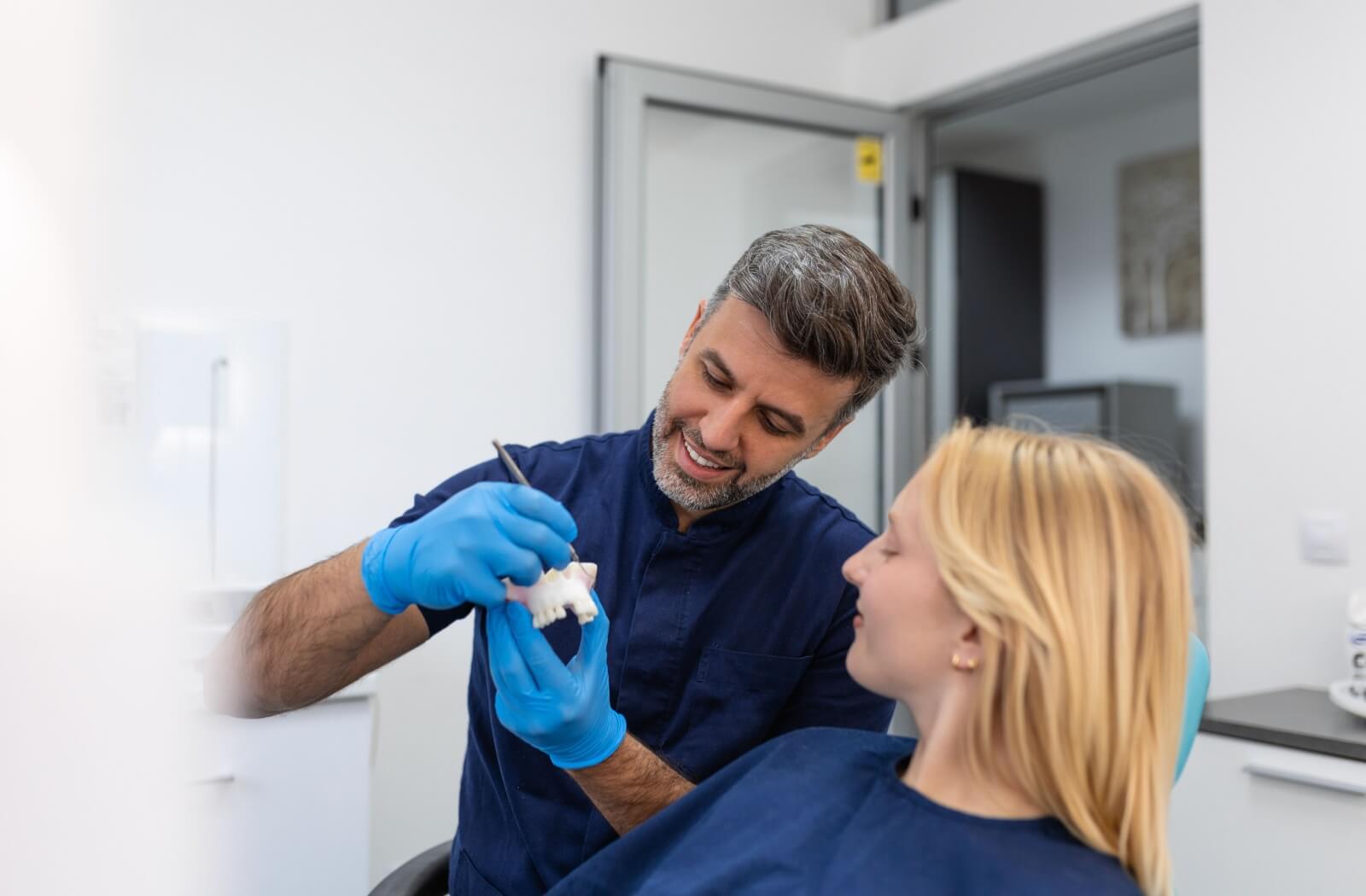 A dental professional shows their patient how they are going to replace a missing tooth.